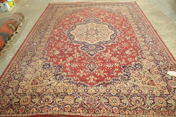 A machine made carpet of Persian design, the red field with a round medallion, 345cm x 250cm.