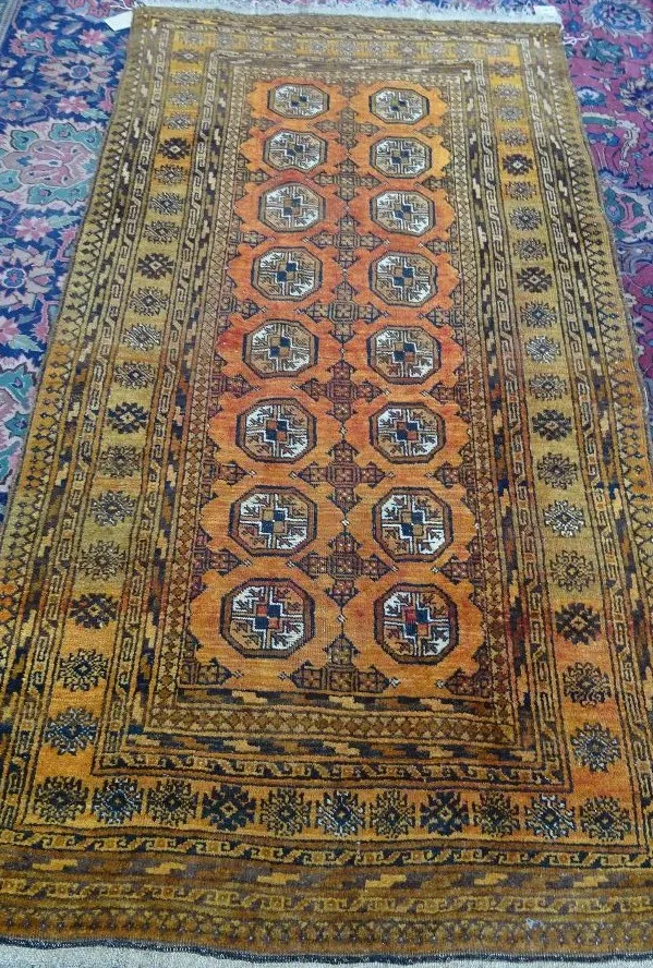 A golden Afghan rug, two columns of seven guls, 200cm x 102cm.