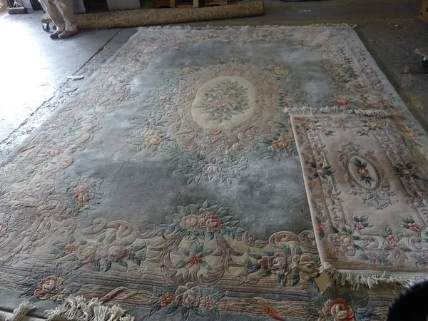 A washed Chinese carpet embossed with flowers and leaves around a central oval on a blue grey ground, 370cm x 220cm, and a similar smaller rug (2).