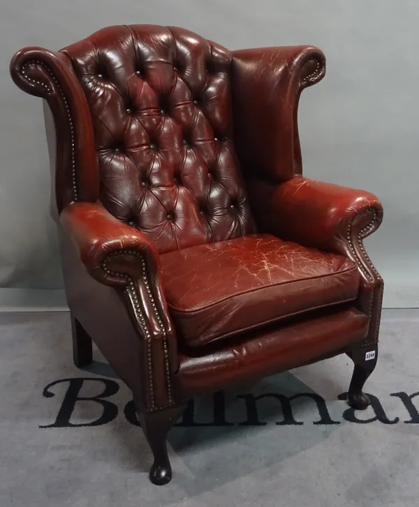 A George III style leather upholstered wingback armchair on cabriole supports and pad feet, 79cm wide x 100cm high.