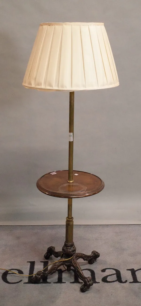 A combination brass and mahogany standard lamp occasional table, on a cast metal paw foot base, 38cm diameter.