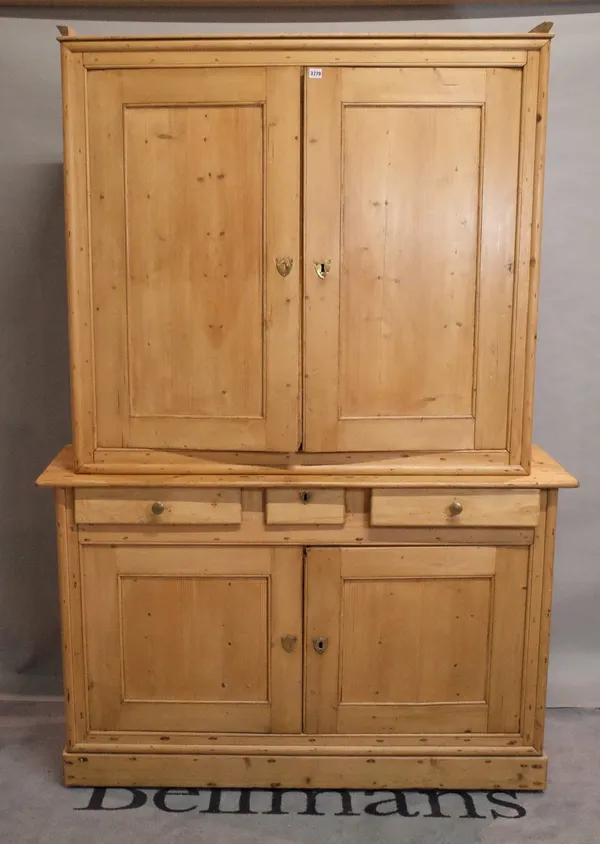 An early 20th century pine housekeepers cabinet with two pairs of cupboard doors divided by three drawers, 145cm wide x 207cm high.