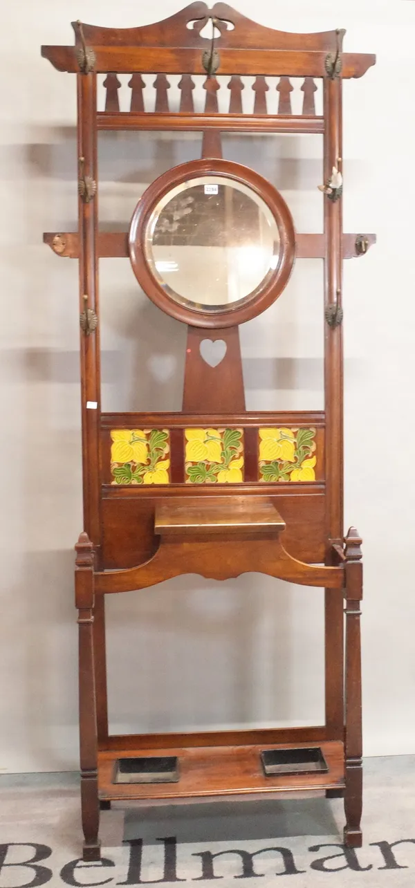 An Art Nouveau mahogany hall stand, inset with a circular mirror and three floral tiles, 86.5cm wide x 33cm deep x 215cm high.