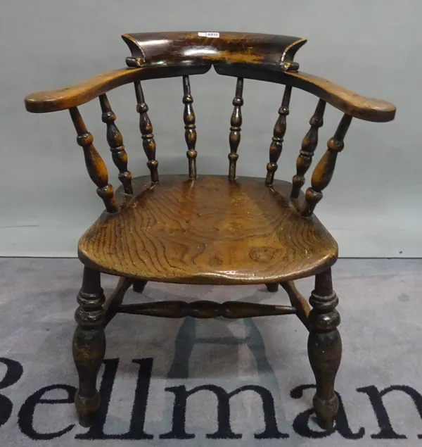 A Victorian elm seated smoker's bow armchair on turned supports, 68cm wide x 73cm high.