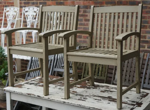 A pair of grey painted hardwood garden open armchairs, 61cm wide x 89cm high.