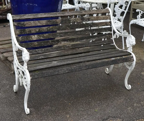 A modern white painted metal and hardwood slatted garden bench with lion mask decorated arms, 130cm wide x 85cm high.