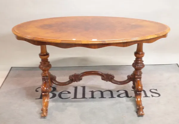 A Victorian style walnut oval centre table on four outswept suports, 138cm wide x 78cm high