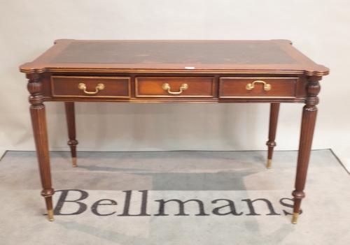 A modern stained beech writing desk, inset leather top over three freize drawers, on reeded, tapering supports, 125cm wide x 76cm high
