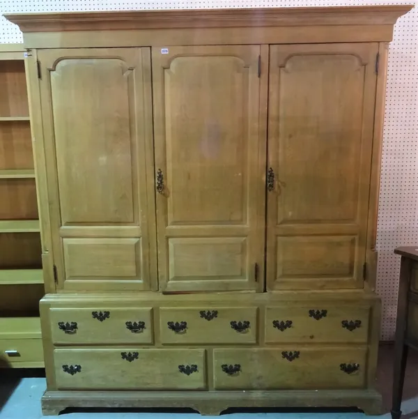 A late George III pine triple wardrobe with three paneled doors over an arrangement of five drawers, 189cm wide x 307cm tall.