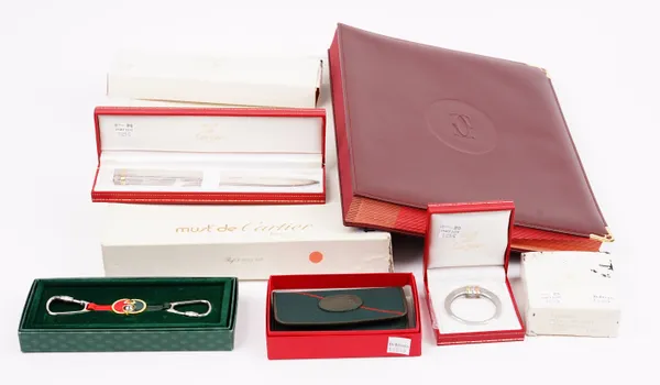 A Must de Cartier tri-colour stainless steel and gold plated money clip, a Must de Cartier paper knife, and signature book, a Gucci keyring and a Le T