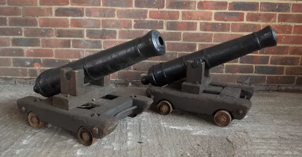 A pair of 20th century black painted imitation cannons, mounted on dollys, length of cannons 82cm.