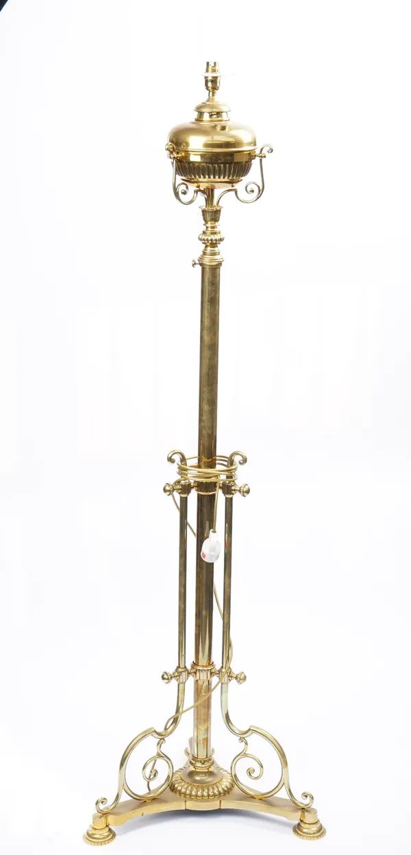 A Victorian brass height adjustable standard lamp (converted), on a scroll frame and three pad feet, 150cm high.