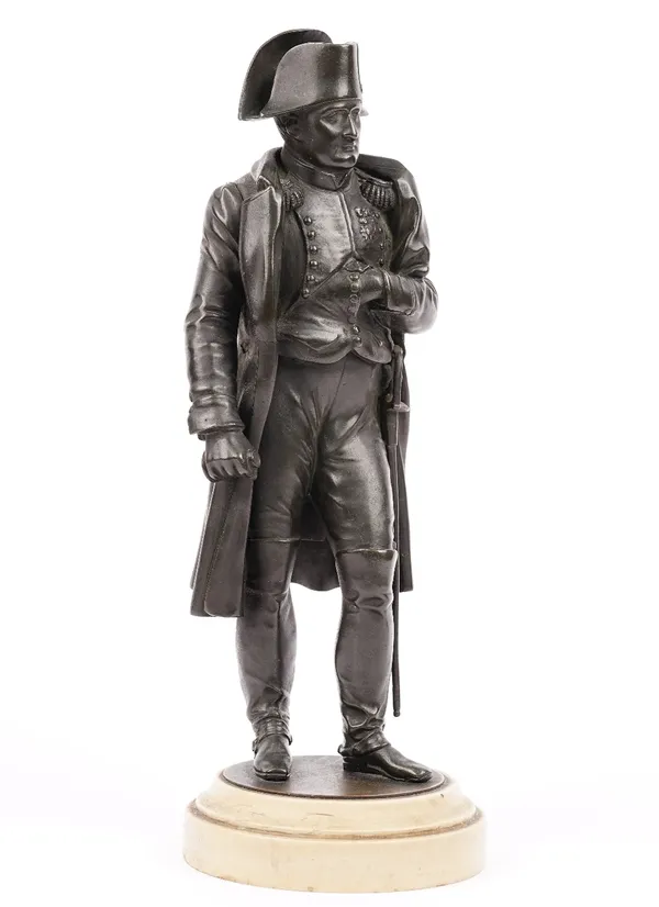 A patinated bronze figure of Napoleon Bonaparte, circa 1900, raised on a circular plinth, 32cm high, unsigned, with a copy of the Napoleon Connoisseur