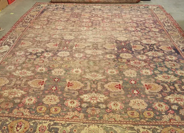 A 19th century Agra carpet, Indian, the aubergene field with an allover floral design of palmettes and other flower heads; a complementary border, 414