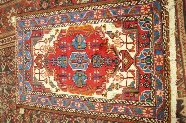 A Hamadan rug, Persian, the ivory held with a large madder medallion, an indigo flower and vine border, 124cm x 84cm.