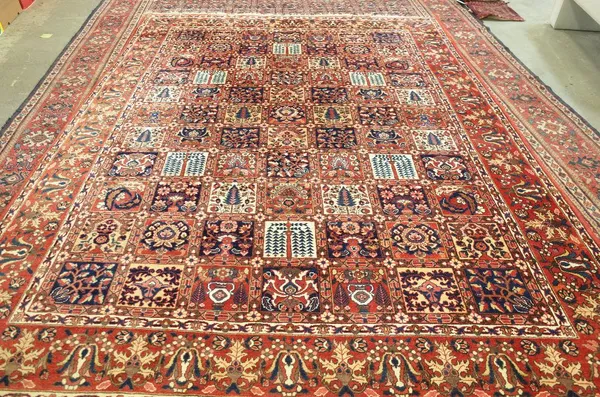 A Bakhtiari carpet, Persian, the field with eleven rows of seven squares each bearing a varied floral design; a madder palmette, vase and vine border,