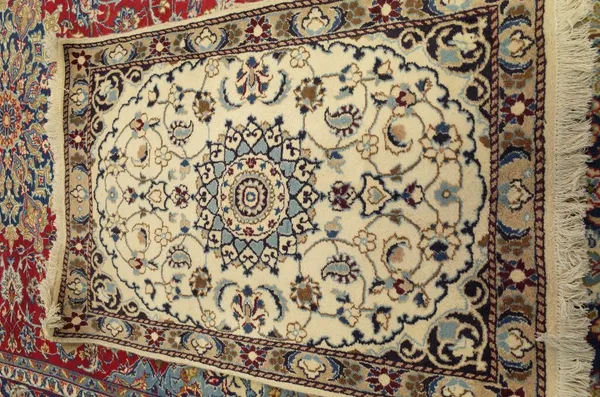 An Esfahan mat, Persian, the ivory field with a central indigo medallion, trailing vines; a beige leaf and flower border, 133cm x 90cm.