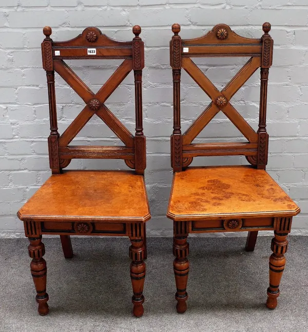 A pair of Gothic Revival oak and walnut hall chairs, with X-frame backs, 46cm wide x 101cm high.