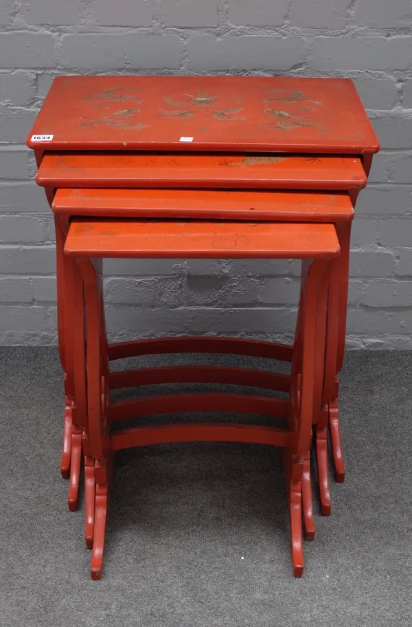 A nest of four 20th century scarlet lacquer occasional tables, on pierced supports, the larger 53cm wide x 70cm high.