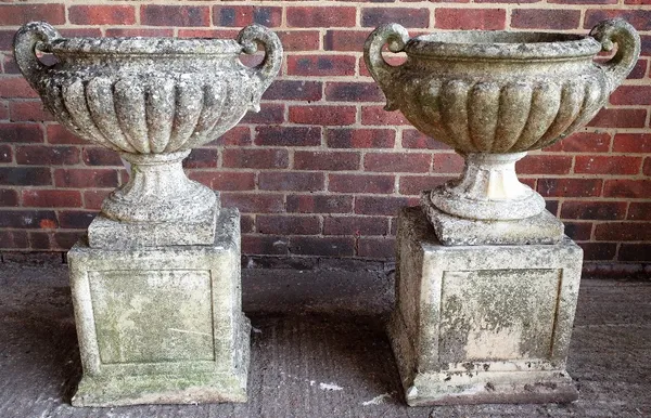 A pair of reconstituted stone, twin handle jardinieres with gadrooned body and turned socle on square bases, 60cm wide x 90cm high.