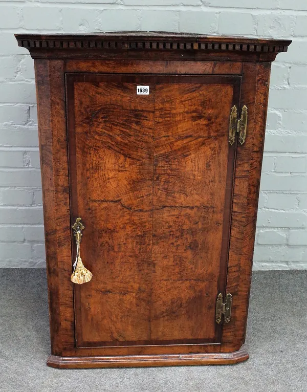 A George III oak and pollard oak wall hanging corner cabinet, the green painted interior with serpentine fronted shelves, the door crossbanded in maho