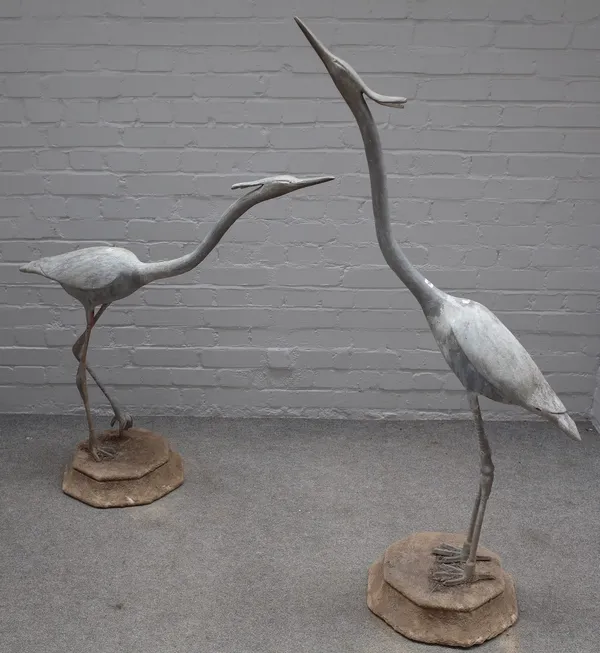 Two architectural lead garden figures of herons, on octagonal reconstituted stone bases, 139cm high and 104cm high, (2).