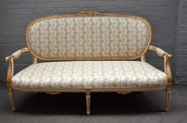 A Louis XVI style painted and gilt framed upholstered settee, 19th century, with ribbon mouldings, on turned and fluted legs, 173cm wide x 102cm high.