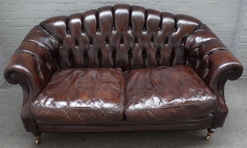 A Victorian style button upholstered brown leather hump back Chesterfield style sofa, on turned supports, 163cm wide x 85cm high.