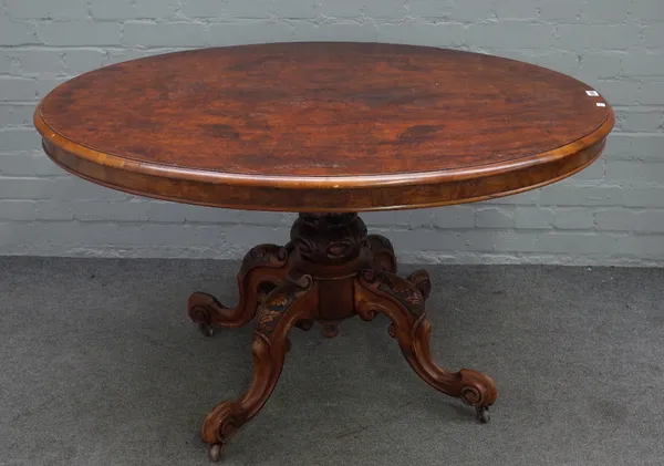 A Victorian figured walnut oval snap top loo table on four carved supports, 122cm wide x 71cm high.