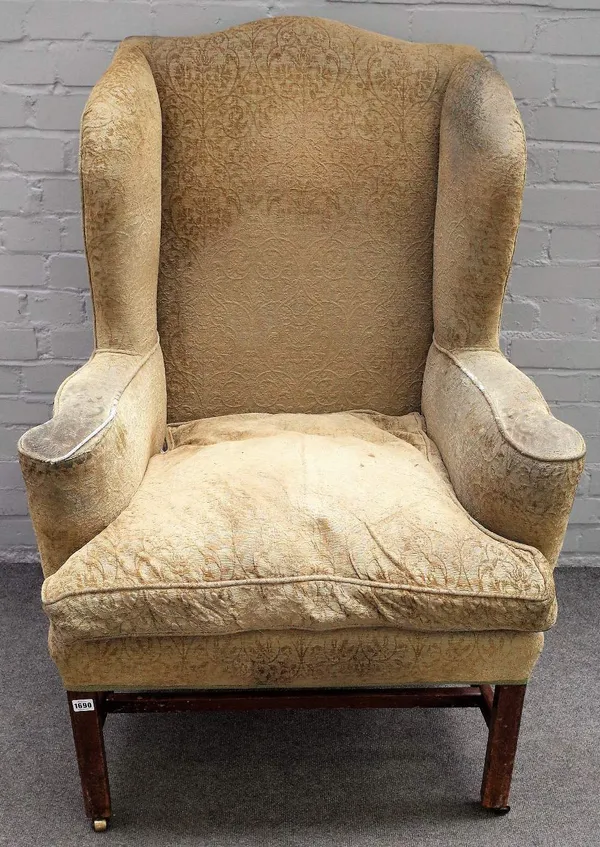 An early 18th century mahogany wingback armchair, on block supports, united by stretchers, 85cm wide x 120cm high.