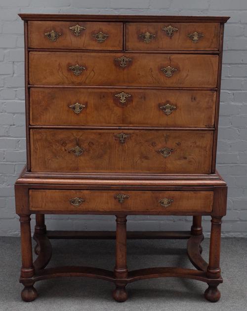 An early 18th century crossbanded walnut chest on stand, with two short over three long graduated drawers, the later stand with single drawer on turne