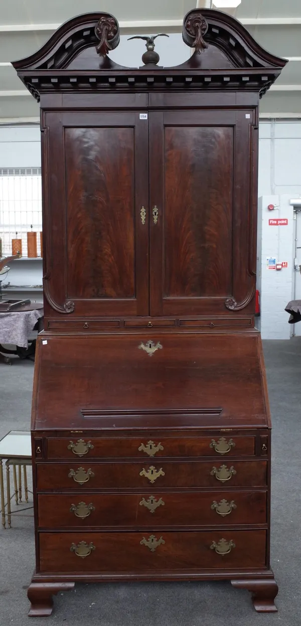 A George III mahogany bureau bookcase, the swan neck cornice over a pair of panelled doors and candle slides, the fitted interior over four long gradu