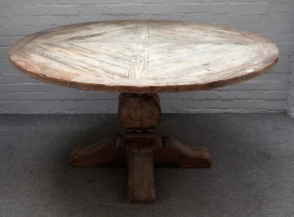 A pine circular table with distressed finish, on square baluster supports, 150cm diameter x 78cm high.