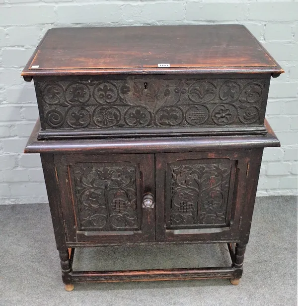 An 18th century oak bible box on stand, with carved panel front over a cupboard base on turned supports, 73cm wide x 84cm high.