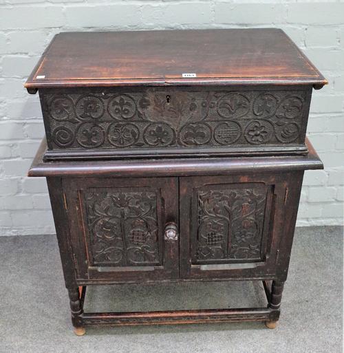 An 18th century oak bible box on stand, with carved panel front over a cupboard base on turned supports, 73cm wide x 84cm high.
