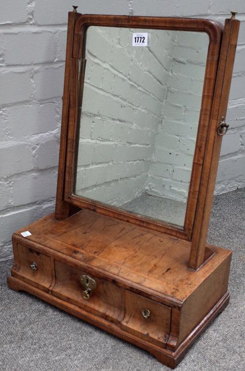 A George II figured and featherbanded walnut toilet mirror, with a three drawer base, on bracket feet, 41cm wide x 54cm high.