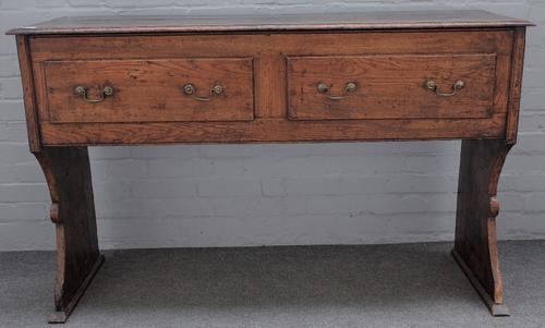 An 18th century elm and oak dresser, possibly West Country, with four frieze drawers on slab trestle supports, 143cm wide x 88cm high.