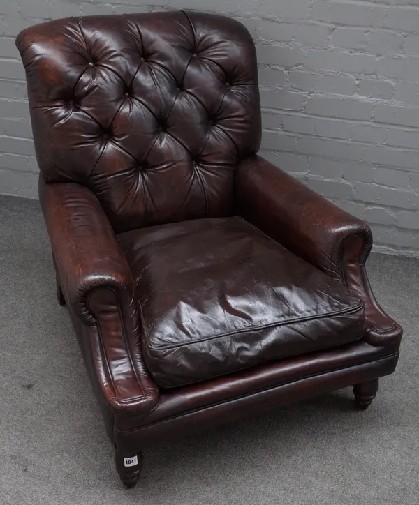 A brown leather button back upholstered easy armchair, on turned supports, 80cm wide x 85cm high.