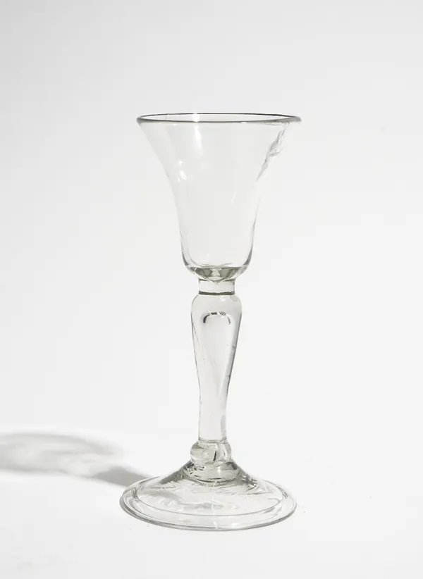 A gin glass, circa 1740, the bell bowl raised on a teared baluster stem and folded foot, 14cm. high.