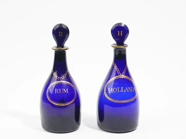 A near pair of blue glass club shaped decanters and stoppers, 19th/20th century, labelled in gilt for `Holland' and `Rum', the lozenge stoppers gilt w