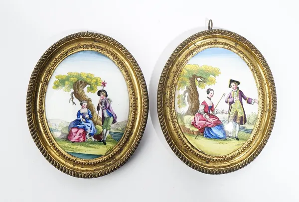 A pair of small English enamel oval plaques, late 18th century, each printed and coloured with a couple in a landscape, 9.5cm. by 7.5cm., gilt metal f