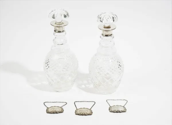 A pair of silver mounted faceted glass decanters and stoppers, London 1965, three silver decanter labels, detailed Sherry, Whisky and Brandy, various