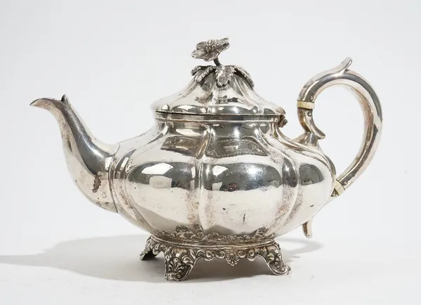 A Victorian silver teapot, of compressed panelled form, the hinged lid having a flower finial, raised on four scalloped feet, London 1843, gross weigh