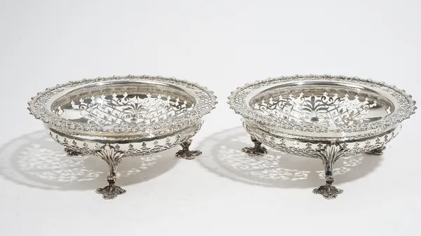 Two similar silver sweetmeat stands, each of shaped circular form, with scroll and geometric pierced decoration, raised on three trefoil shaped feet,