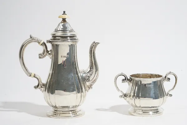 A silver coffee pot, together with a matching twin handled silver sugar bowl, each of baluster form, with panelled decoration, raised on a circular fo