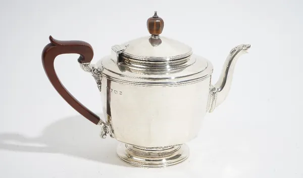 An Art Deco three piece silver tea service, by Selfridge & Co, Birmingham 1930, of panelled circular form, the teapot with wooden scroll handle and fi