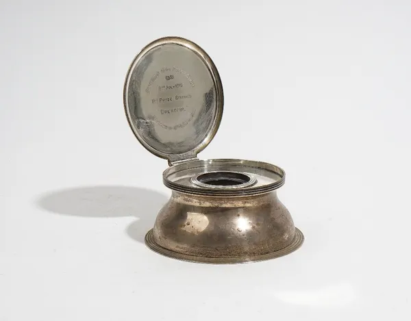 A capstan shaped silver inkwell, by Asprey, Birmingham 1918, the hinged cover enclosing a cut glass liner, 11cm diameter, inscribed 'Heythrop Hunt Pup