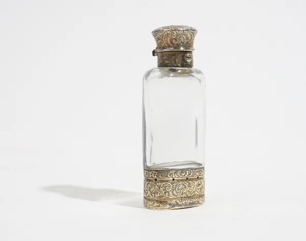 A Victorian silver gilt mounted colourless glass scent bottle cum vinaigrette of oval form, the mounts with feathered scroll engraved decoration, make