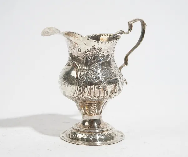 A George III silver cream jug, of pear shaped form, embossed with Dutch style scenes of a girl milking a cow and of a swan, height 10cm, London 1779,