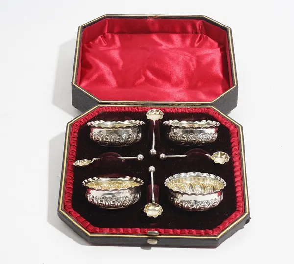 A set of four Victorian silver salts, each of shaped circular form, with embossed decoration, Birmingham 1888 and a matching set of four silver salt s